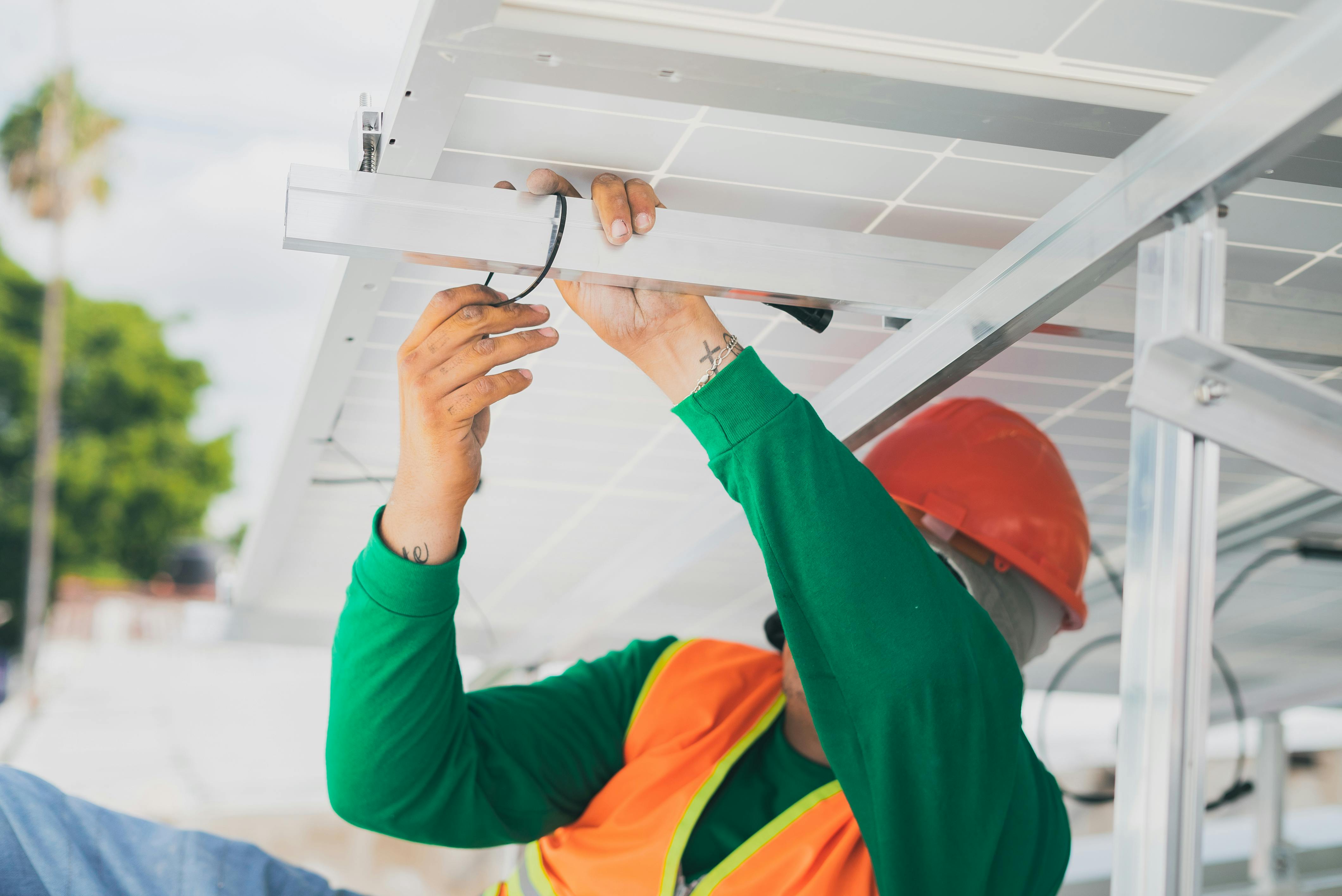 Technician working on electrical connections beneath a solar panel